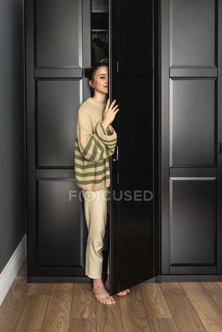 Mujer de pie junto a la puerta del armario en casa — Stock Photo