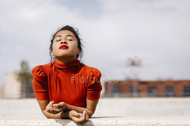 Young beautiful woman with eyes closed leaning on retaining wall — Stock Photo