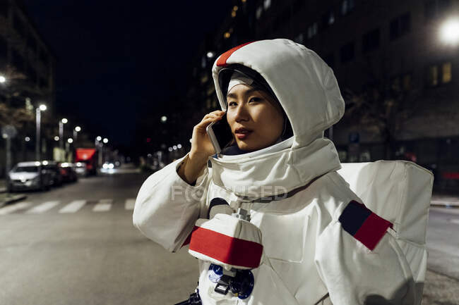 Female astronaut talking on smart phone at night — Stock Photo