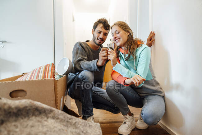 Feliz joven pareja sosteniendo la llave en su nuevo hogar - foto de stock