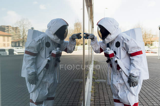 Astronauta maschio in tuta spaziale toccare parete di vetro in città — Foto stock