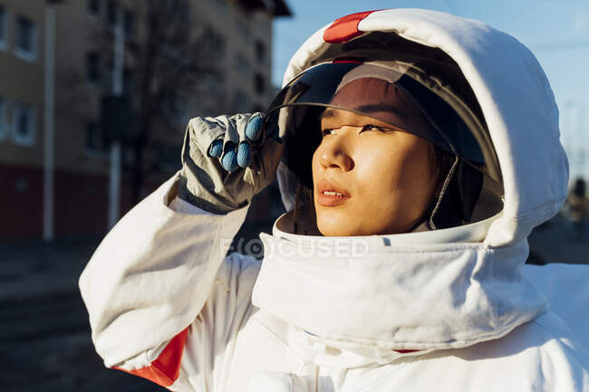 Female astronaut looking away while opening space helmet during sunset — Stock Photo