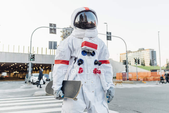 Male astronaut with skateboard at crosswalk in city — Foto stock