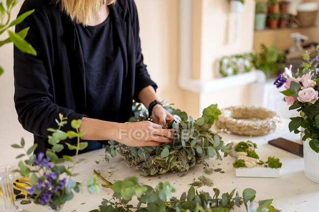Female florist making flower arrangement from leaves at workshop — Stock Photo