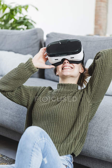 Sorrindo mulher em suéter segurando realidade virtual fone de ouvido em casa — Fotografia de Stock