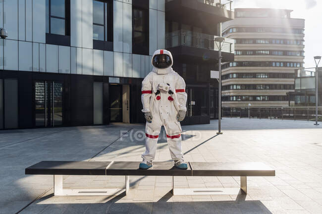 Male astronaut standing on bench in city - foto de stock