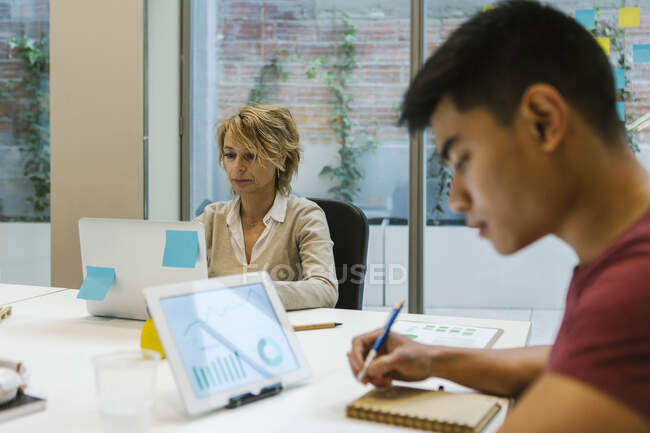 Male and female entrepreneurs working at hot desk in office — Stock Photo