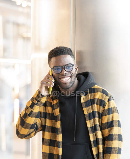 Sonriente hombre hablando en el teléfono móvil delante de la columna - foto de stock