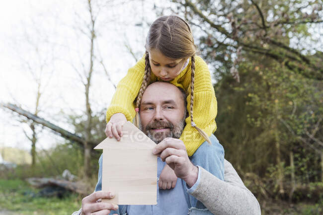Father with house model carrying daughter on shoulder — Stock Photo