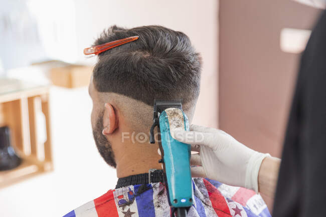 Parrucchiere maschile che taglia capelli di cliente con macchina a salone — Foto stock