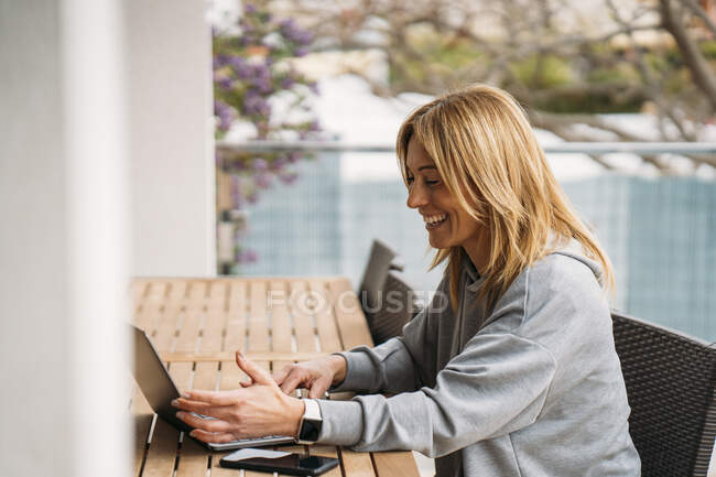 Lächelnde Berufstätige mit Laptop auf Balkon zu Hause — Stockfoto