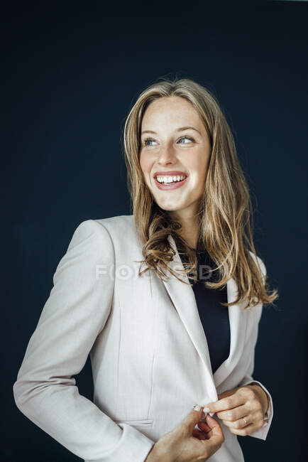 Усміхнена жінка - професіонал проти синього фону, дивлячись у далечінь. — стокове фото