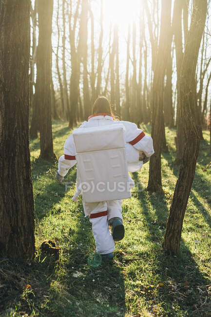 Female astronaut wearing space suit running in forest — Foto stock
