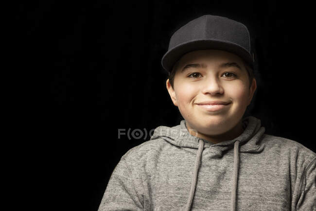 Усміхнений хлопчик у шапці перед чорним фоном. — стокове фото