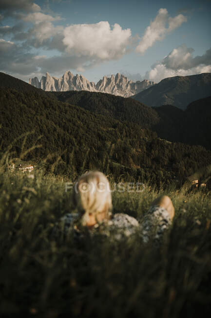 Woman lying on grass while looking at dolomites mountain ranges in South Tyrol, Italy — Stock Photo