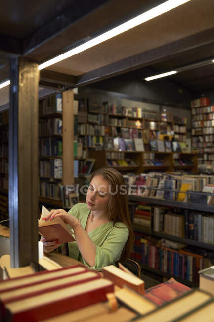 Studentessa cerca libro in biblioteca — Foto stock