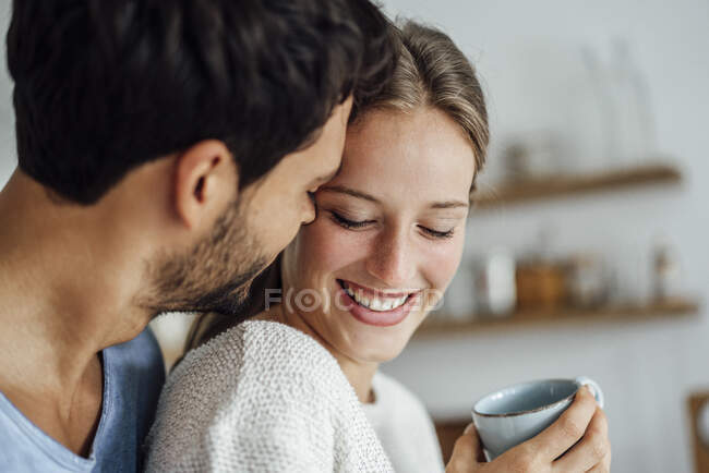 Jeune homme embrassant femme souriante à la maison — Photo de stock