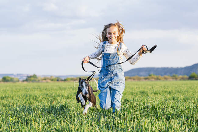 Счастливая девушка, бегающая с собакой на поле — стоковое фото