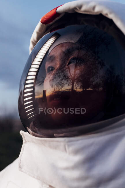 Astronauta donna che distoglie lo sguardo con riflesso di luce illuminata sul casco durante il tramonto — Foto stock