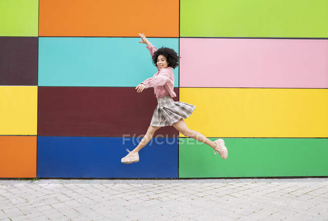 Unbekümmerte junge Frau springt mit ausgebreiteten Armen auf Fußweg — Stockfoto