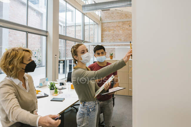 Young businesswoman explaining business strategy to male and female coworkers in office — Stock Photo