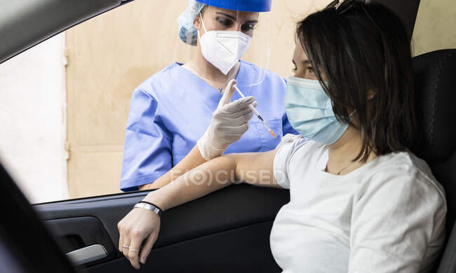 Donna che riceve il vaccino COVID-19 in auto alla guida — Foto stock