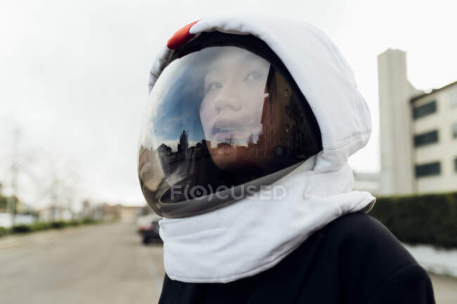 Jovem mulher olhando embora enquanto usava capacete espacial — Fotografia de Stock