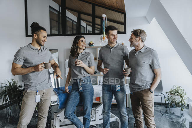 Smiling male and female physiotherapists having coffee in practice — Stock Photo