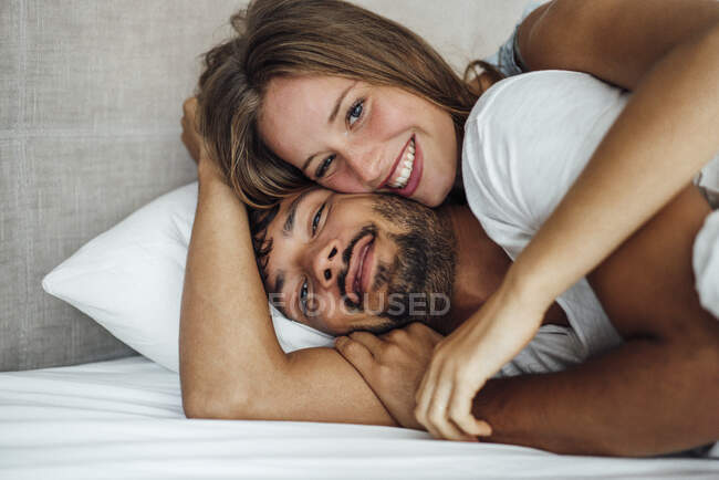 Прекрасна усміхнена жінка лежачи з хлопцем на ліжку. — стокове фото