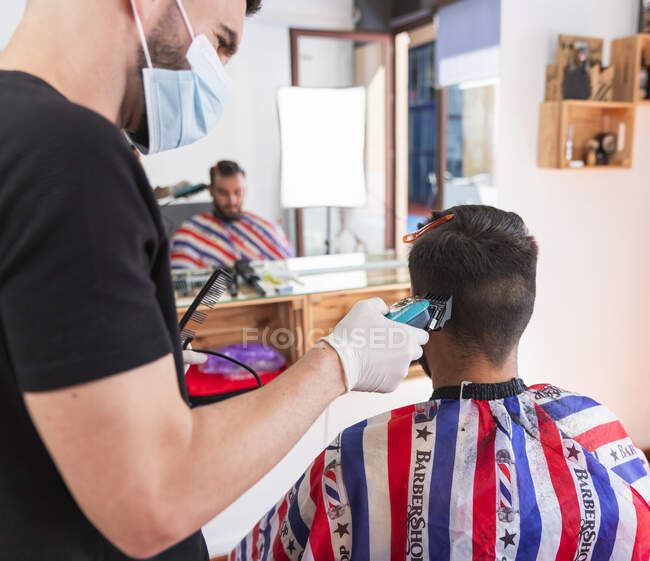 Parrucchiere maschile taglio capelli del cliente con macchina al negozio di barbiere — Foto stock