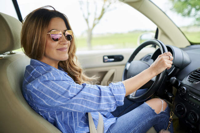 Smiling woman with sunglasses driving car — Stock Photo