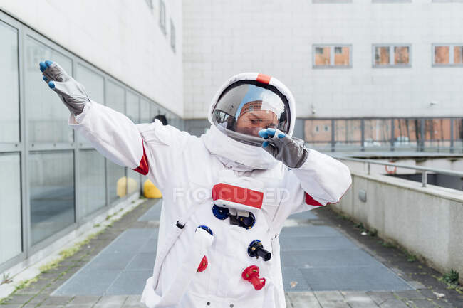Astronauta en traje espacial haciendo dab mientras está de pie cerca de la construcción - foto de stock