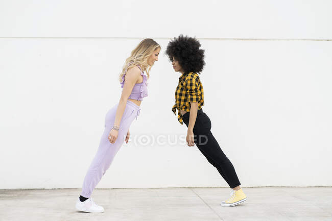 Multi-étnico feminino amigos de pé inclinação por parede — Fotografia de Stock