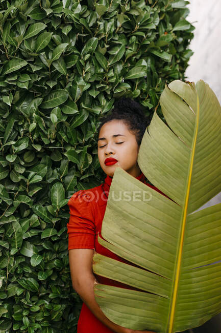 Femme tenant la feuille de banane verte tout en se tenant devant les plantes — Photo de stock