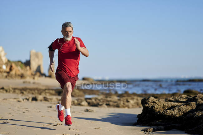 Визначення людини, що біжить на пляжі в сонячний день. — стокове фото