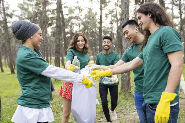 Multiethnische Freiwillige sammeln im Wald Müll in Plastiktüten ein — Stockfoto
