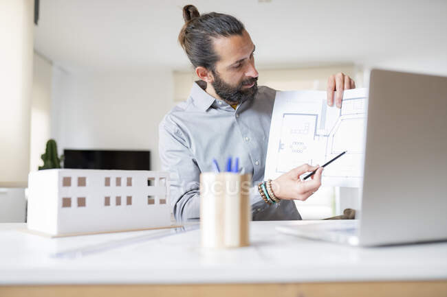 Architecte masculin expliquant plan de construction sur appel vidéo sur ordinateur portable à la maison — Photo de stock