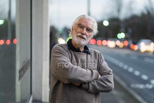 Homme âgé avec les bras croisés debout devant un café — Photo de stock