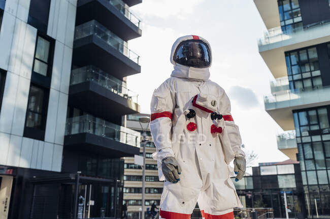 Male astronaut wearing space helmet standing amidst buildings — Foto stock