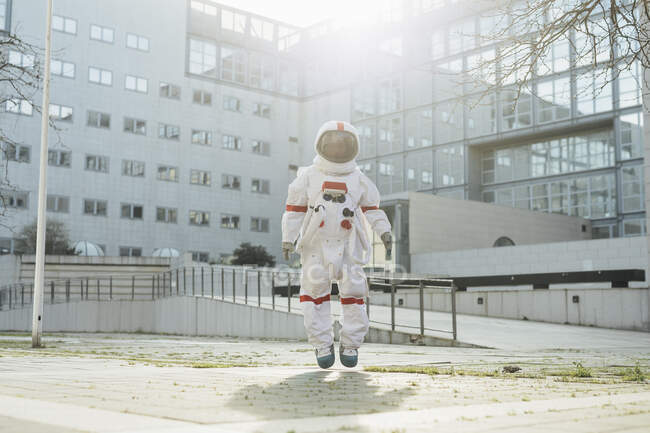 Female astronaut in mid-air on footpath during sunny day — Stock Photo