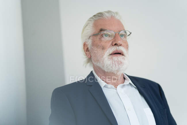 Profesional masculino senior con anteojos soñando despierto en la oficina - foto de stock