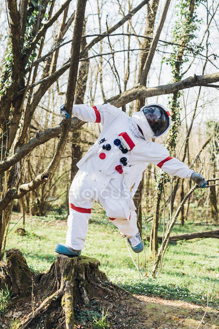 Female astronaut hanging on tree branch in forest — Stock Photo