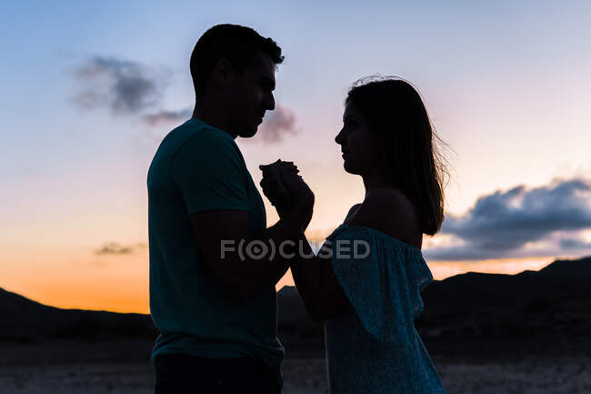 Paar hält Händchen, während es bei Sonnenuntergang im Freien steht — Stockfoto