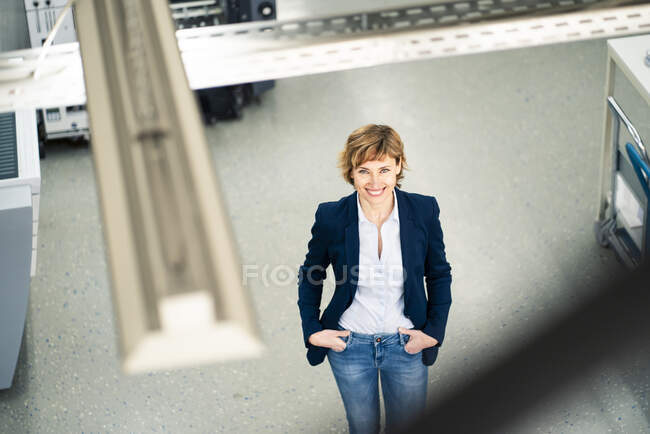 Smiling mature female owner standing with hands in pockets at printing industry — Stock Photo