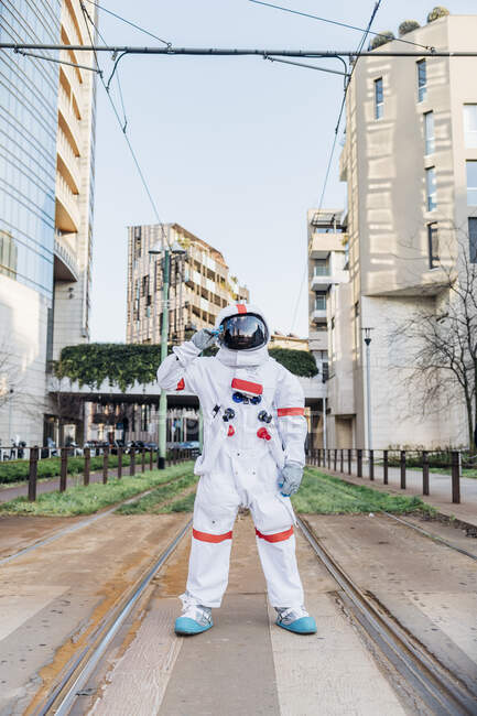 Male astronaut saluting while standing on rail track - foto de stock