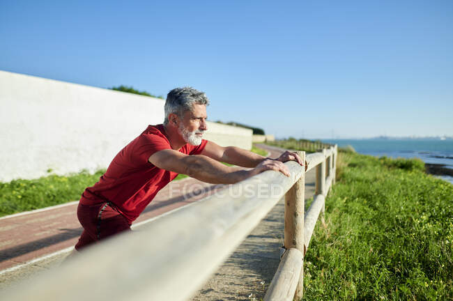 Мужчина, растянувшийся на перилах в солнечный день — стоковое фото