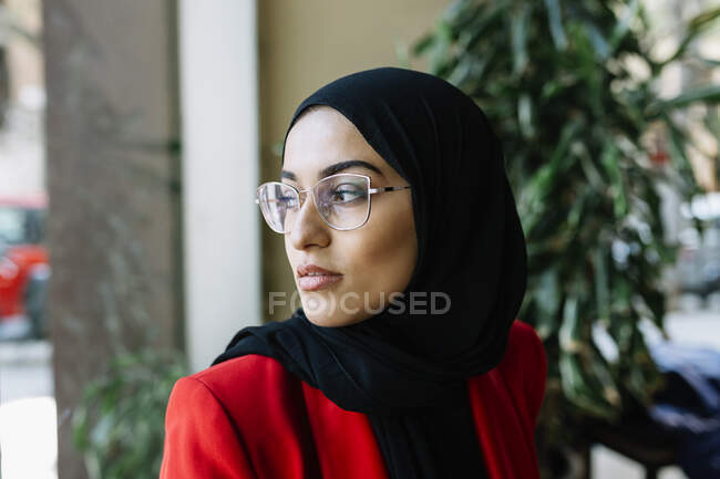 Jovem mulher vestindo óculos contemplando no café — Fotografia de Stock