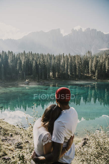 Casal abraçando enquanto olha para a vista perto do lago Carezza no sul do Tirol, Itália — Fotografia de Stock