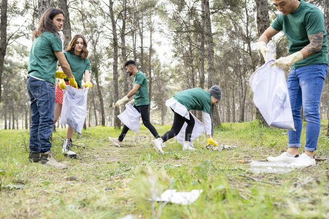 Amigos recogiendo basura plástica en el bosque - foto de stock
