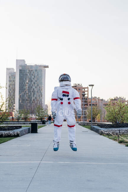Male astronaut jumping at public park — Stock Photo